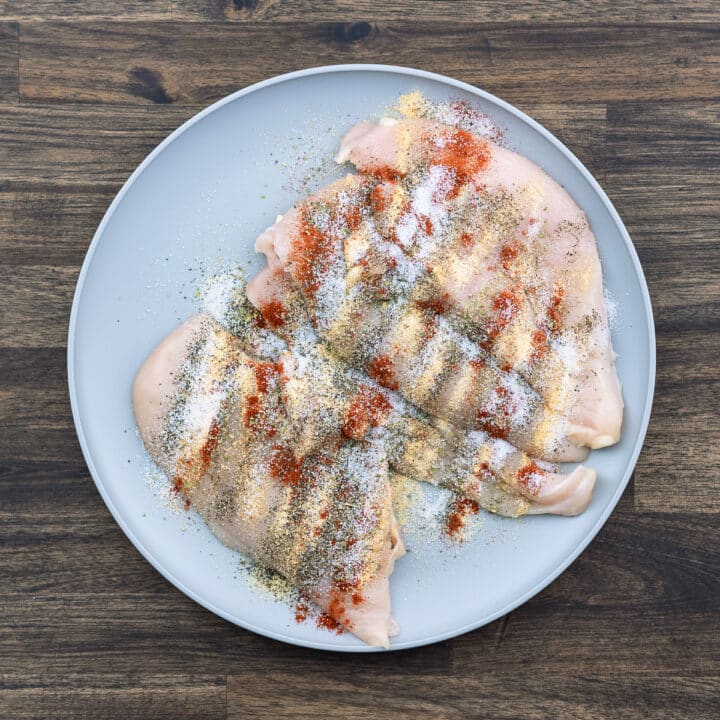 A plate with chicken breast sprinkled with seasoning powders.