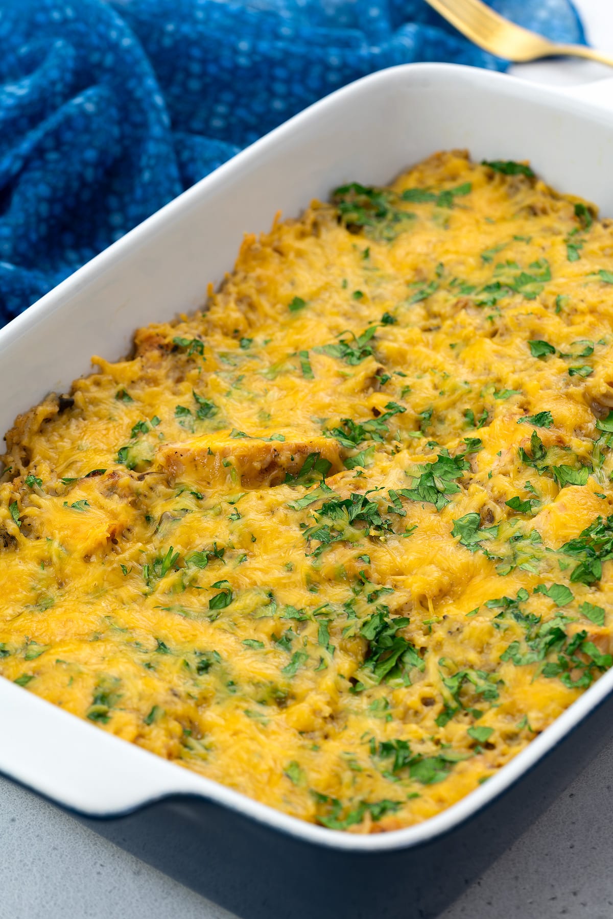 Chicken and rice casserole in a baking dish with a golden fork and blue towel placed around.