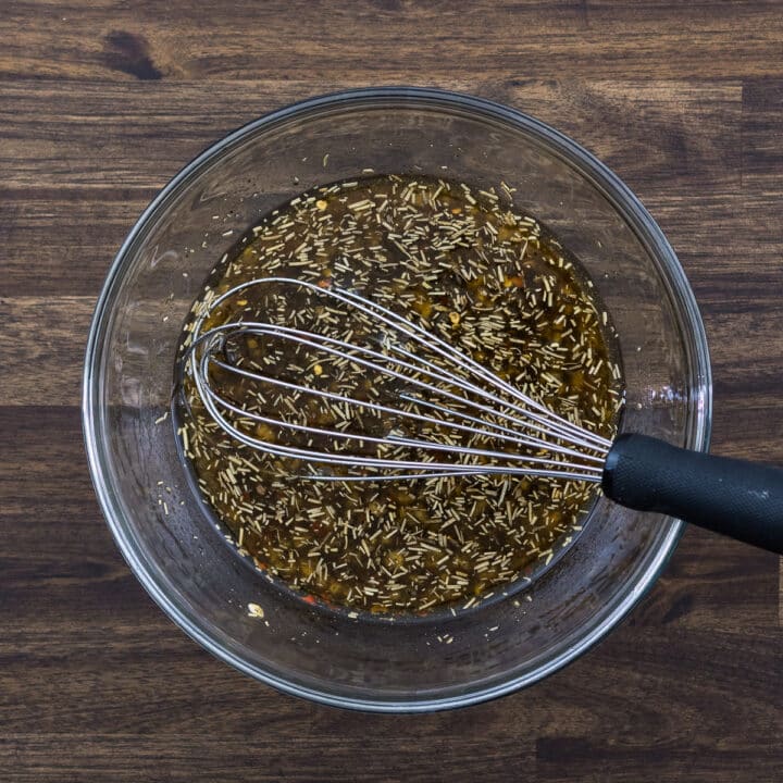 A bowl with chicken marinade mixed using a whisker.