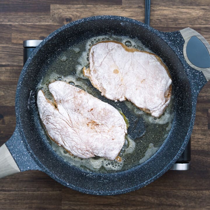 Frying chicken breast in a pan with an oil and butter mixture.