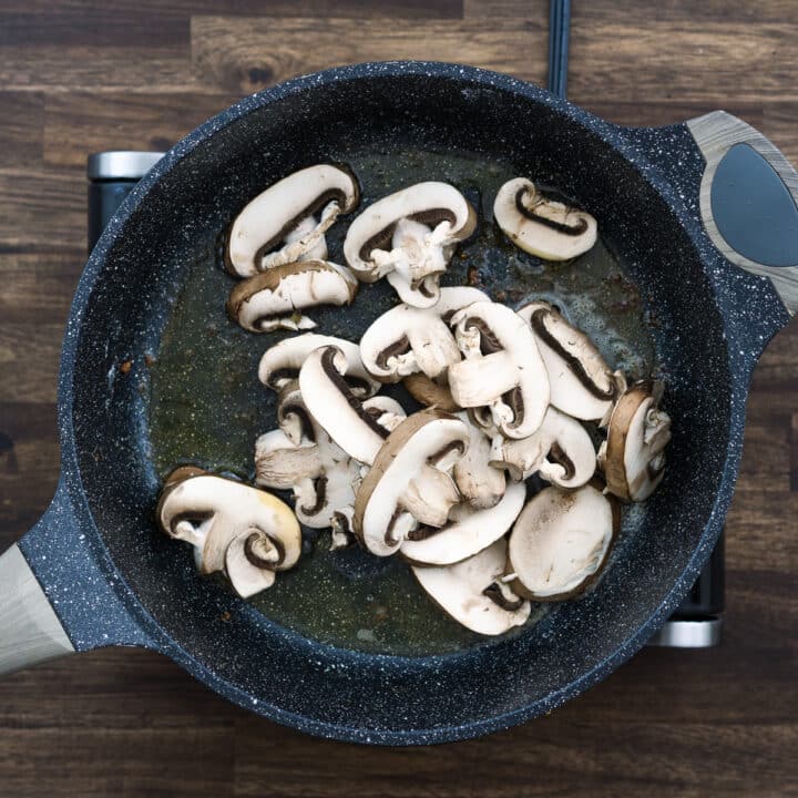 A pan with mushrooms in oil butter mixture.