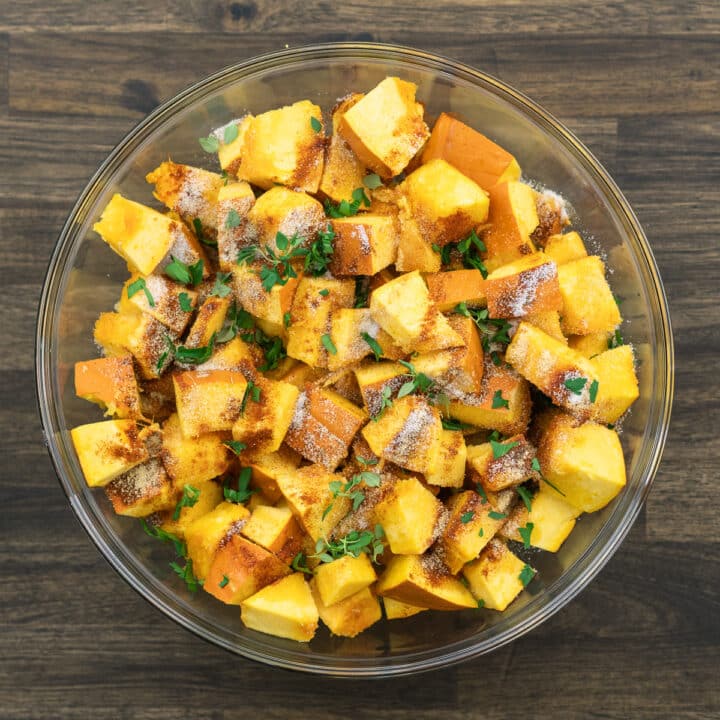 A bowl with seasoned pumpkin with basic seasonings and herbs.