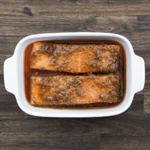 A baking dish with salmon fillets coated in salmon marinade.