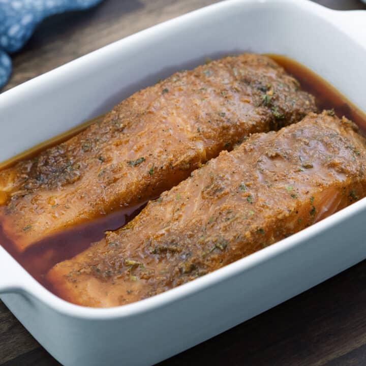 Salmon fillets in a baking dish, generously coated with flavorful marinade.