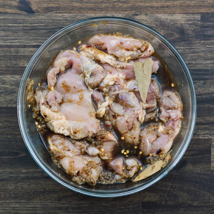 A bowl with chicken thighs in adobo marinade.