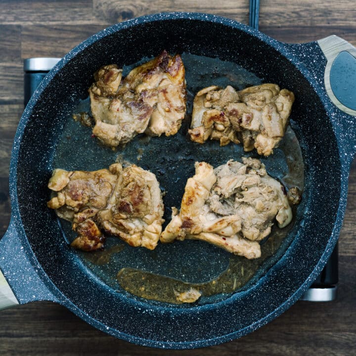 A pan with nicely seared chicken thighs.