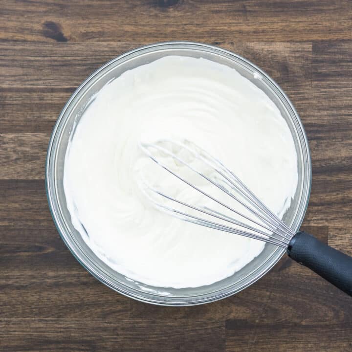 A bowl with whisked sour cream, cream cheese and mayo.