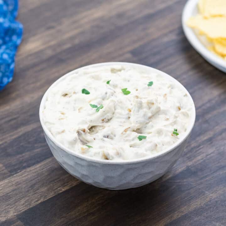 French Onion Dip served in a white bowl with potato chips.