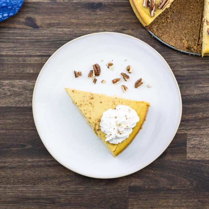 Pumpkin Cheesecake topped with whipped cream served in a white plate.