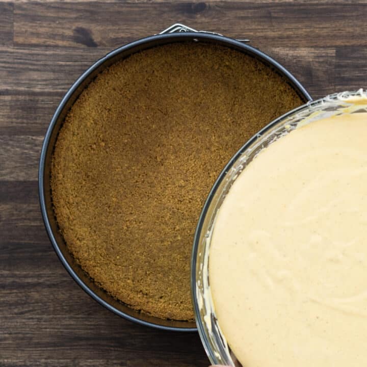 Adding the baked crust with pumpkin cheesecake filling.