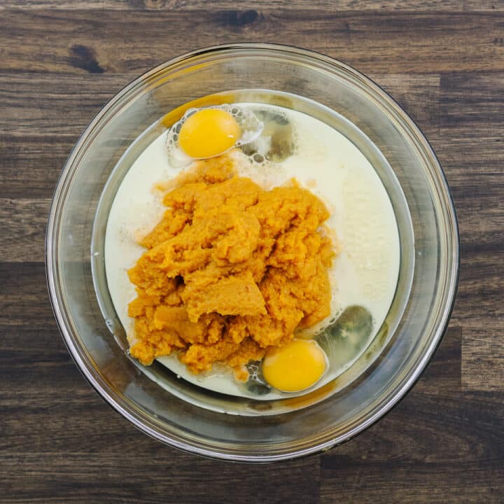 A bowl with eggs, milk, pumpkin puree and brown sugar.