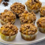 Oval-shaped plate with pumpkin muffins on a white table, accompanied by star anise and a cinnamon stick nearby.