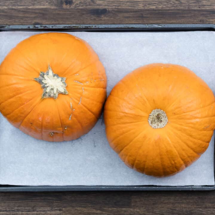 Halved pumpkin on a baking tray lined with parchment paper.