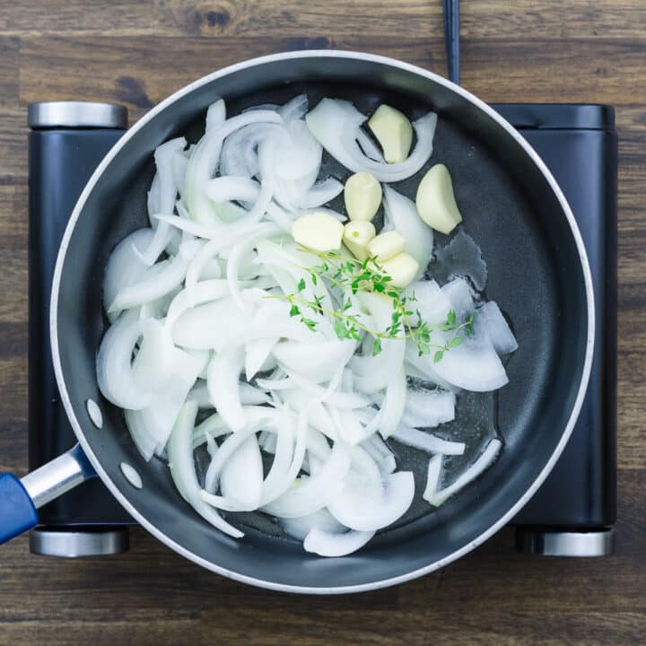 A pan with onion, garlic and thyme leaves.