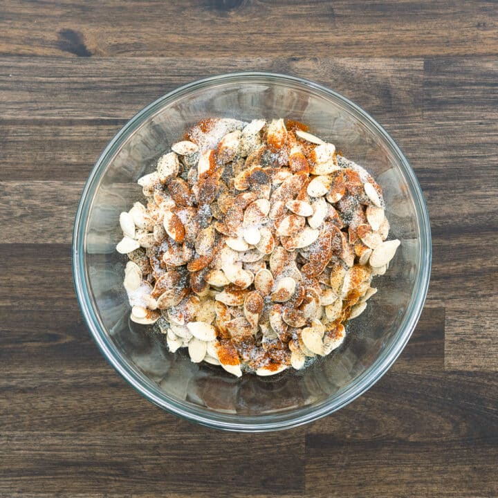 A bowl with pumpkin seeds and seasoning powders.
