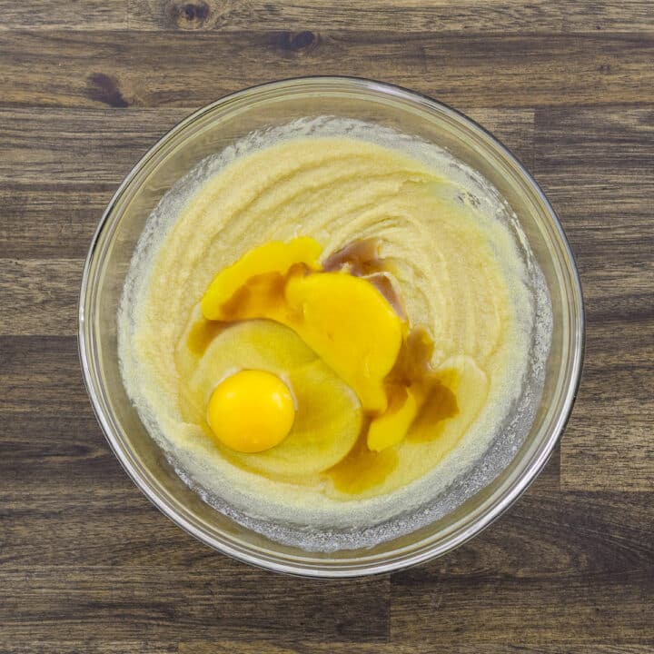 A bowl with eggs, egg yolk, and vanilla essence added to the butter-sugar mixture.