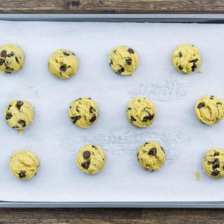 Chocolate chip cookie dough placed in a baking tray lined with parchment paper.