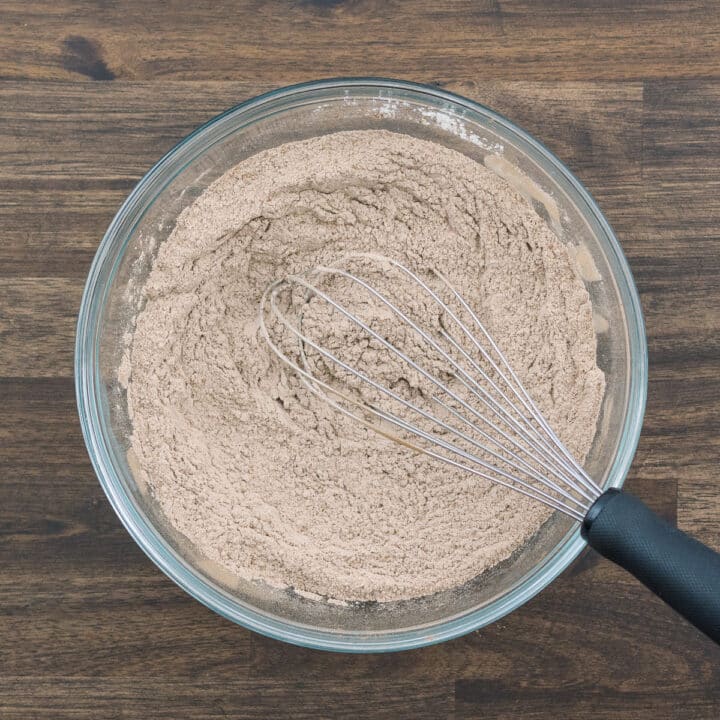 A bowl with flour, cocoa, baking soda, and salt all mixed up with a whisk.