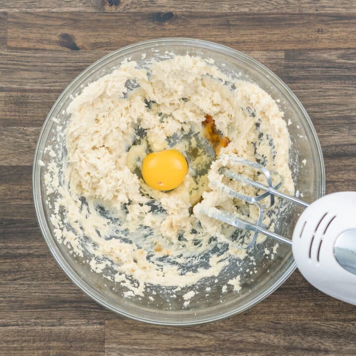A bowl with butter, egg, and vanilla extract with the electric beater.