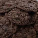 Stacked homemade double chocolate chip cookies, showcasing their rich texture and abundance of chocolate chips.