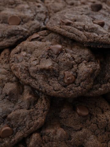 Stacked homemade double chocolate chip cookies, showcasing their rich texture and abundance of chocolate chips.