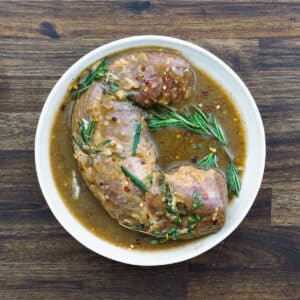 A bowl with pork loin marinating in a pork tenderloin marinade.