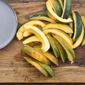 Sliced acorn squash displayed on a wooden cutting board.