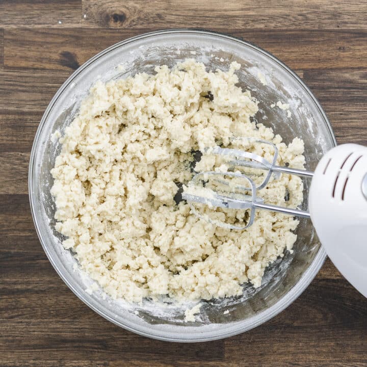 Bowl with crumbled flour mixture prepared with an electric beater.