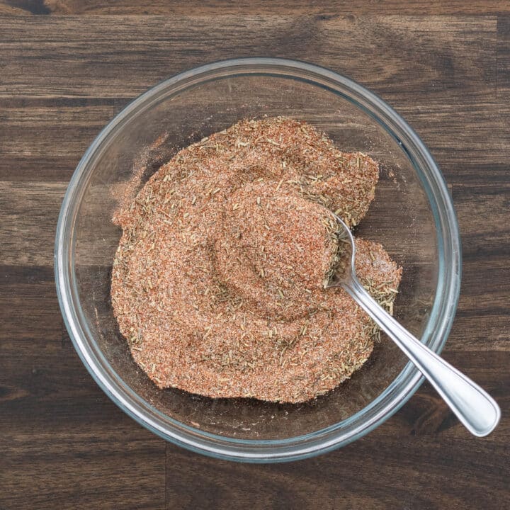 A bowl with a spoon mixing the ingredients for steak seasoning.