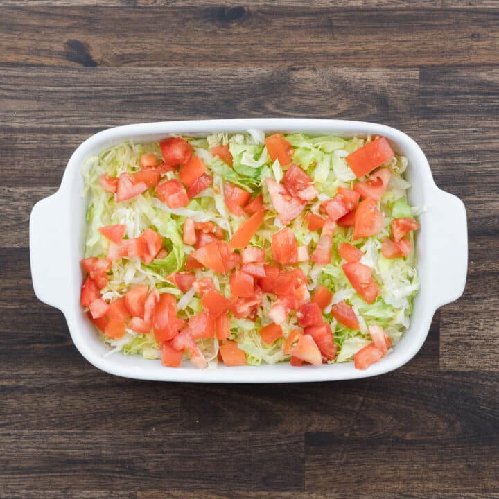 A shallow tray displaying a creamy base layered with crisp lettuce and juicy tomatoes.