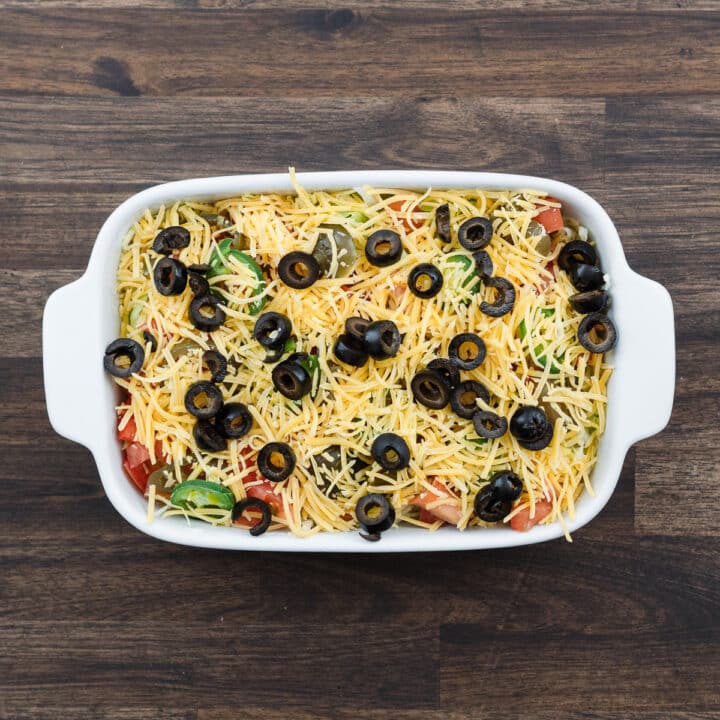 A shallow tray displaying the final layer of olives and cheese.