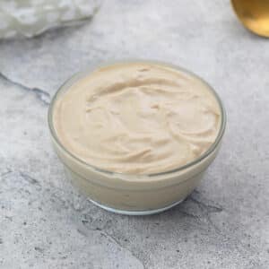 Tahini Sauce in a clear glass bowl on a white table.