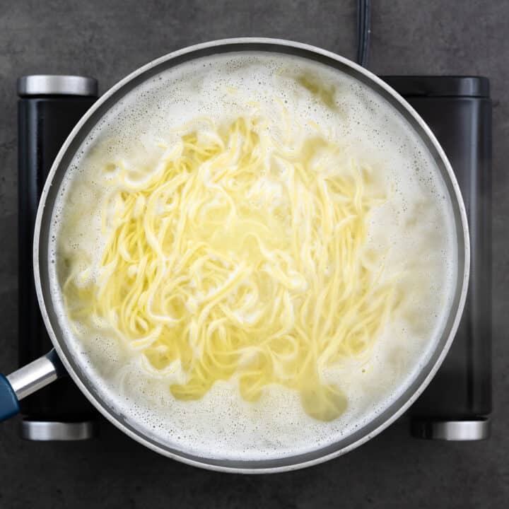 A pan showcasing the cooking process of Chow Mein noodles.