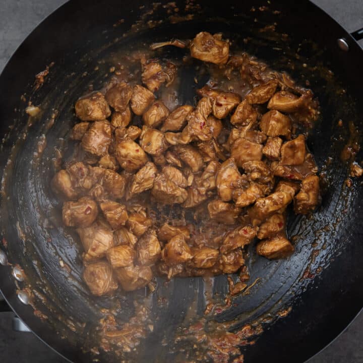 A wok with chicken in the stir frying process.