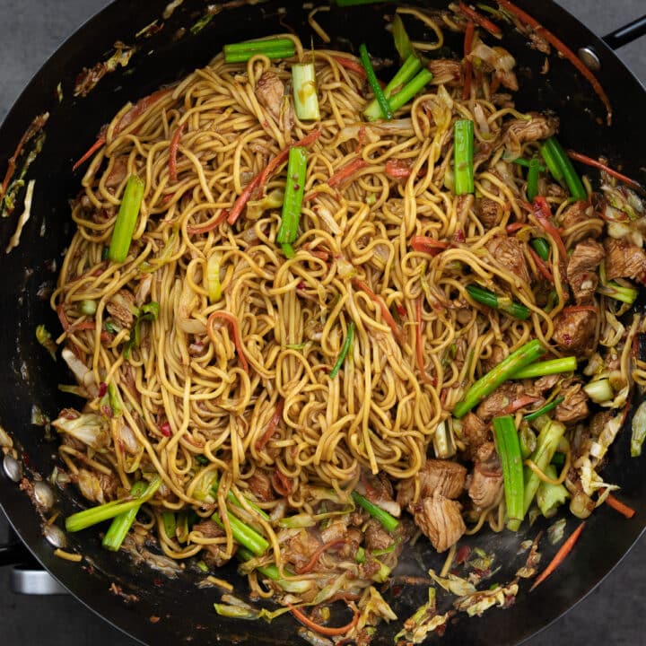 A pan presenting Chicken Chow Mein noodles, garnished with spring onions.