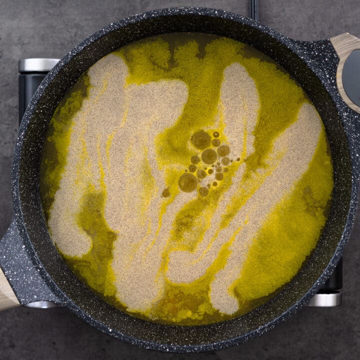 A pan with tasty chicken broth seasoned with white pepper, sesame oil, salt, sugar, and turmeric.