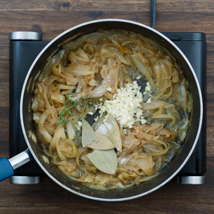 Aromatic herbs enhancing caramelized onions in a pan.