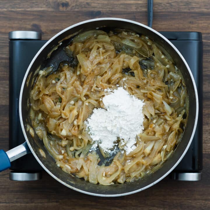 Herb-infused caramelized onions with all-purpose flour in a pan.