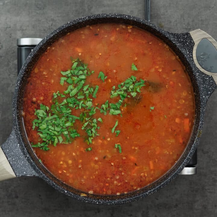 A pan showcasing lentil soup garnished with fresh parsley leaves, adding a burst of color and freshness.