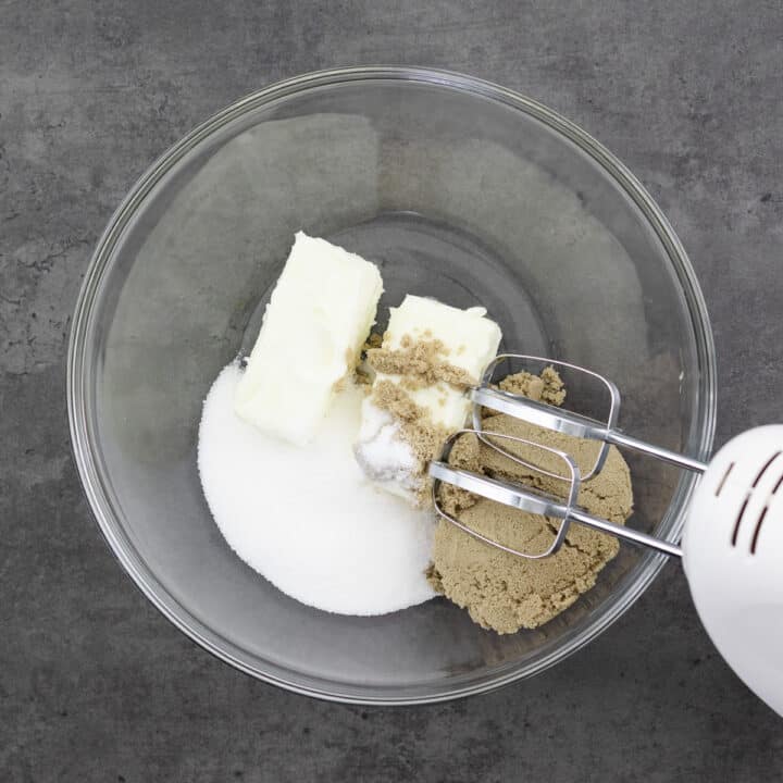 Butter, brown, and white sugar in a bowl, ready to be beaten with an electric beater.