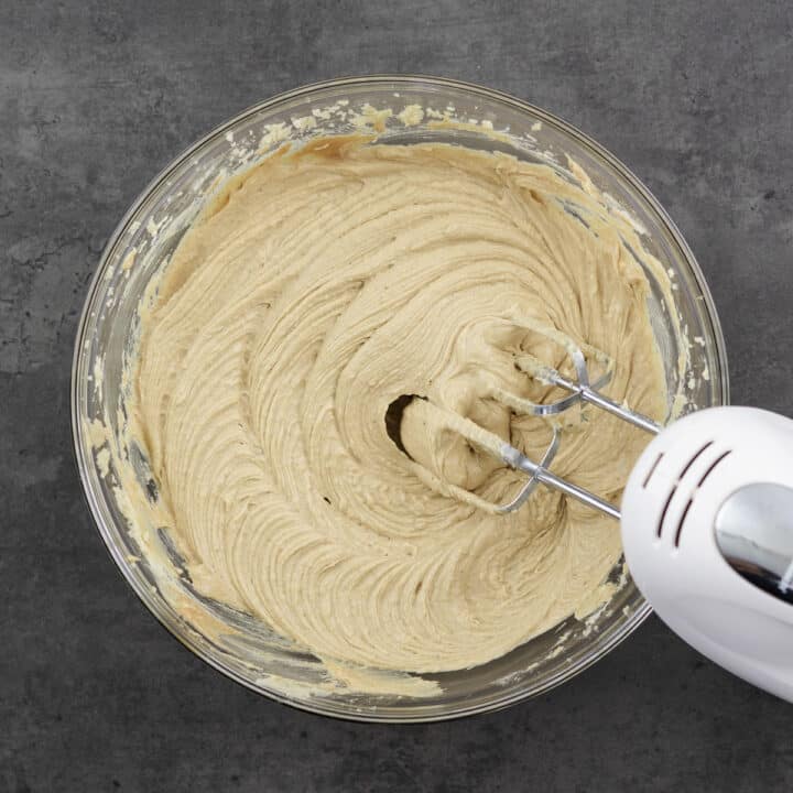 Bowl with a smooth mixture of creamy peanut butter, eggs, and sugar, blended with a beater.