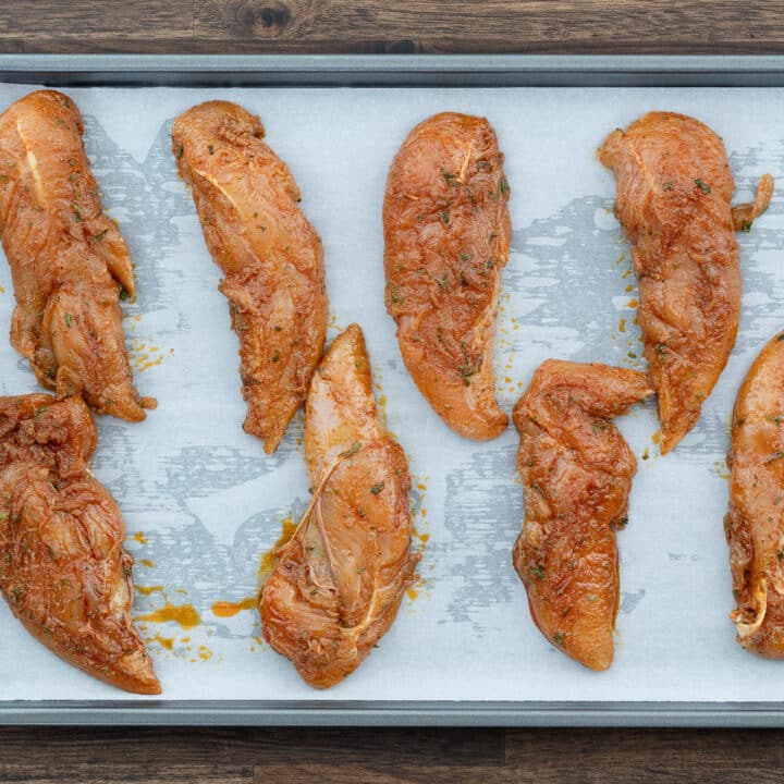 A baking tray displaying marinated chicken tenders, showcasing the anticipation of a delicious baking process.