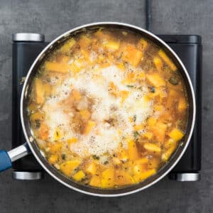 A pan with butternut squash boiling in the broth.