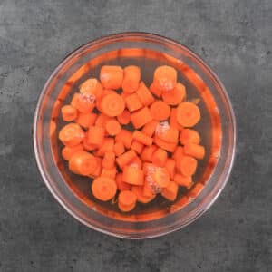 A bowl containing carrots soaking in warm water.
