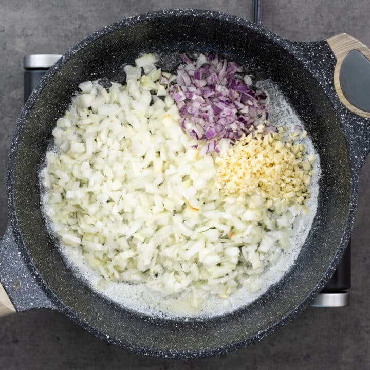 Pan with aromatic onions, shallots, and garlic cooking in a butter-oil mixture.