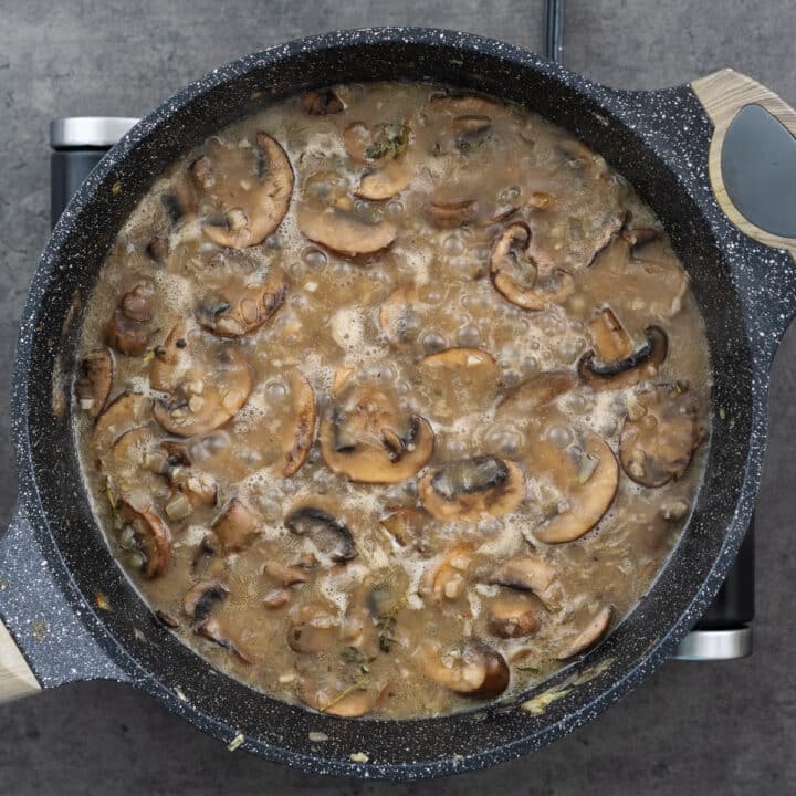 Pan with mushrooms simmering in beef and chicken broth.
