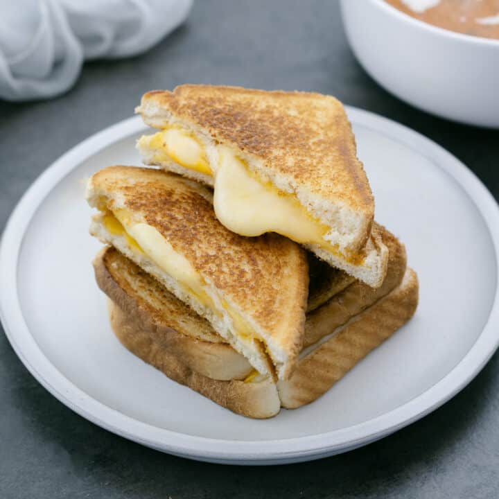 A Grilled Cheese Sandwich served on a plate with tomato soup alongside. A Grilled Cheese Sandwich served on a plate with tomato soup alongside.