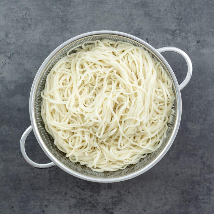 A colander with cooked egg noodles.