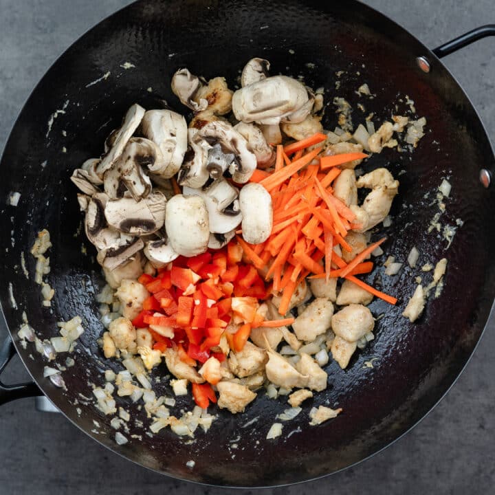 A wok with cooked chicken and tender veggies.