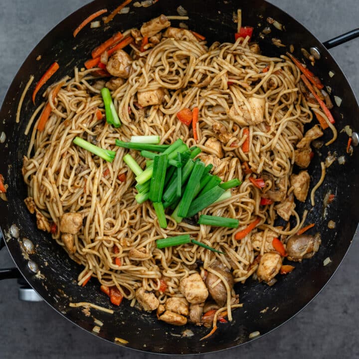 A wok with Lo Mein noodles and spring onions.